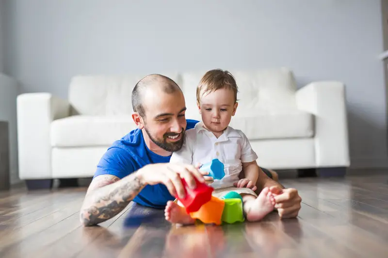 young father showing his toddler how to put together some basic cup shaped toys