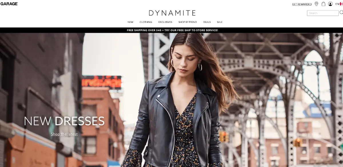 This is a screenshot of the Dynamite Clothing website showing a girl in a stylish black leather jacket worn with a floral print summer dress. A sample of the styles available from Dynamite. 