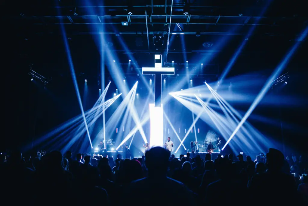 This is a photo of a cross/crucifix hanging above a stage at a Christian rock concert with stage lighting around it