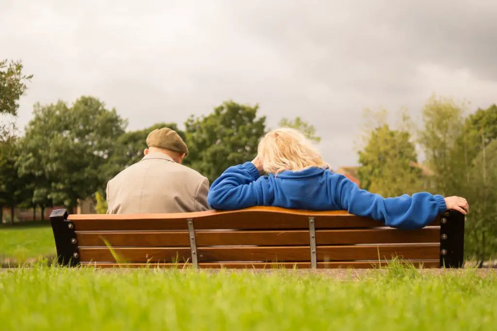 An older couple sitting on a bench in a park to represent senior living affiliate programs