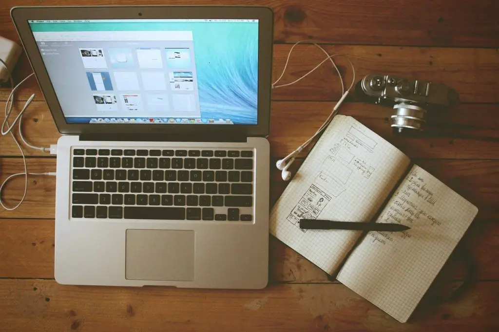 a laptop and notebook on a desk to show blogging with wordpress plugin affiliate programs